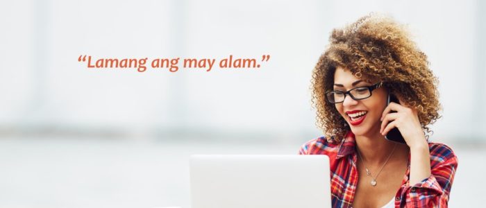 Woman holding phone in front of laptop.